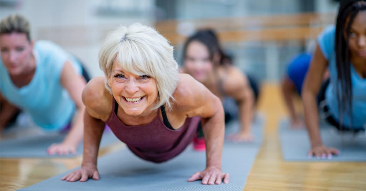 Træning for stive led: Ældre dame der er i træningscenteret og ser glad og smilende ud.