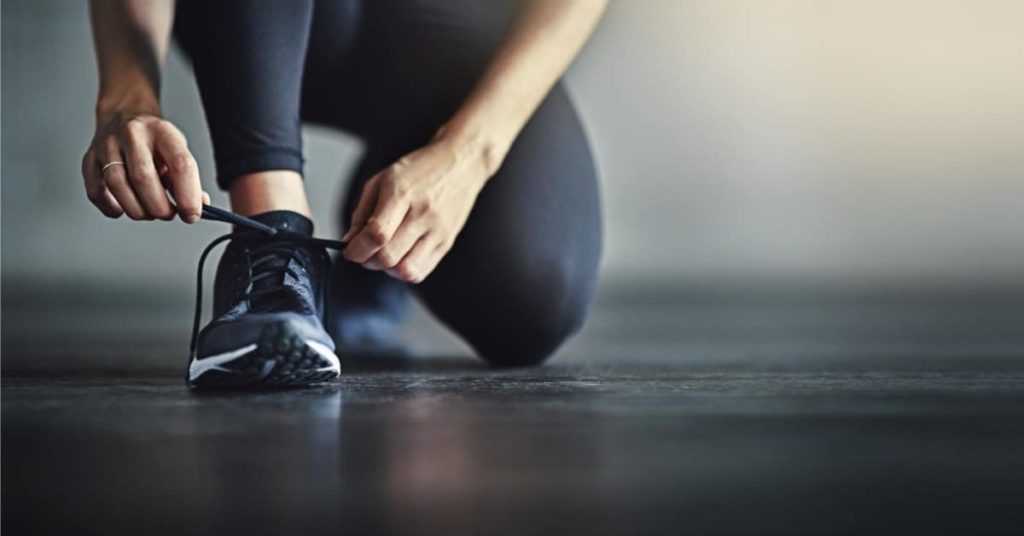 Stive led og sko: Kvinde der snørrer sine snørrebånd på træningssko.